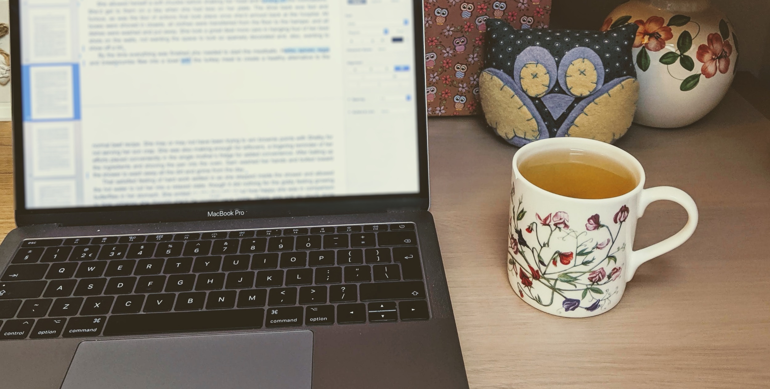 A picture of a laptop, flowered mug, and stuffed owl